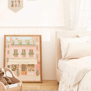 Charming Parisian bakery illustration in soft pink tones, displayed in a cozy bedroom setting, evoking a serene, romantic ambiance.