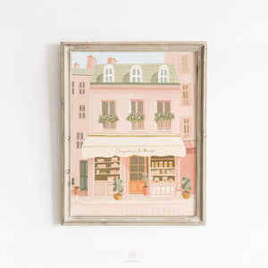 Elegant pink-toned Paris market building artwork featuring a quaint bakery with flowers and baked goods, presented against a clean white backdrop.