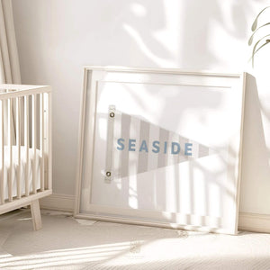 Seaside flag art print in a modern nursery with natural sunlight and minimal decor, by artist Leah Straatsma